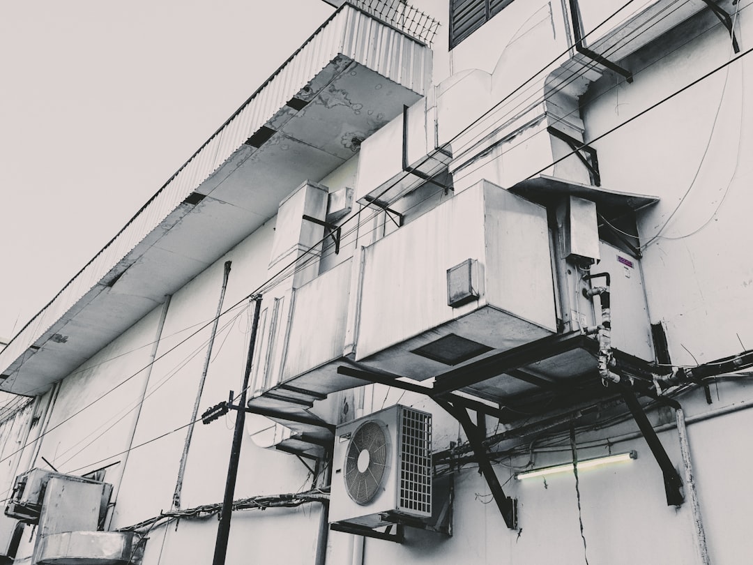 Home a-black-and-white-photo-of-an-air-conditioner-on-the-side-of-a-building-y7ajnqa-78i